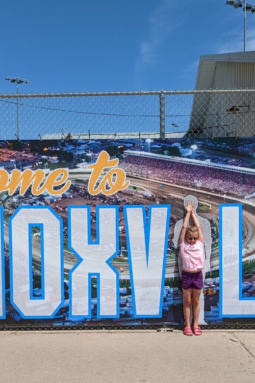 photo of Ada standing where the "i" would be in front of a sign that says Knoxville