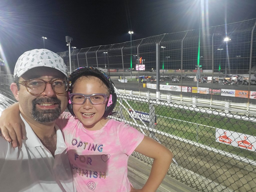 photo of Zach and Ada with frontstretch of Knoxville Raceway behind them
