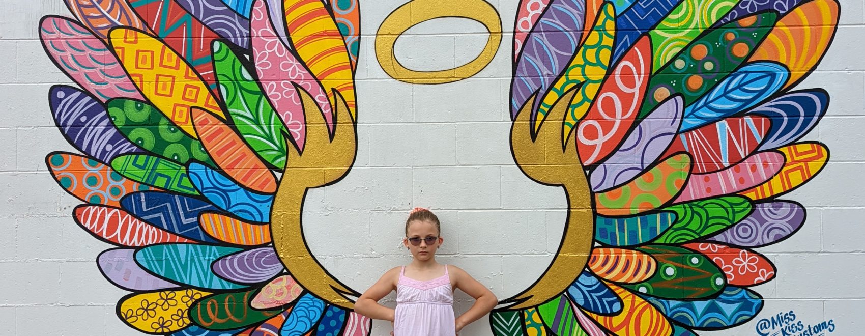 Ada standing in front of a mural of wings