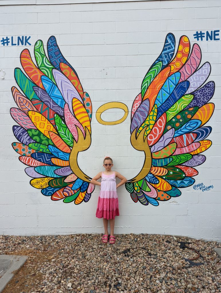 Ada standing in front of a mural of wings