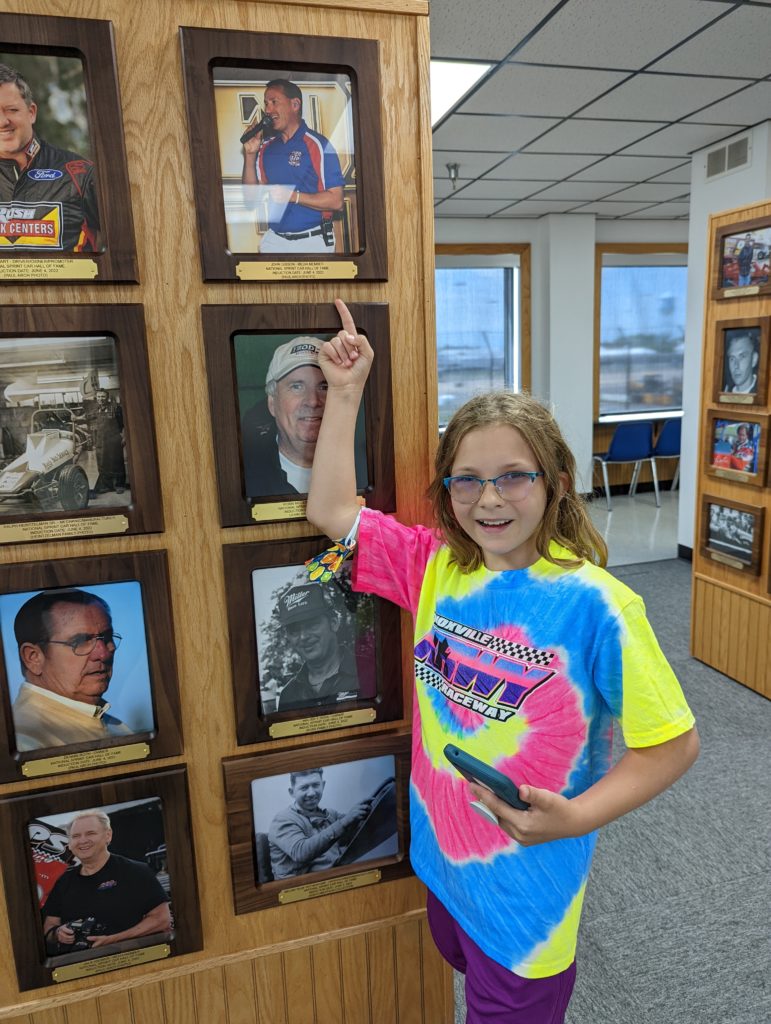 photo of Ada pointing to John Gibson plaque in Hall of Fame