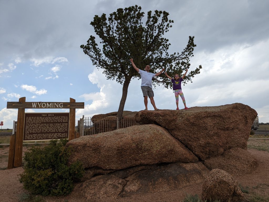 photo of Zach and Ada standing in front of the "tree in a rock" roadside attraction