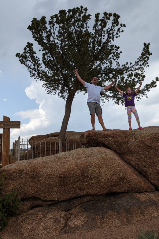 photo of Zach and Ada standing in front of the "tree in a rock" roadside attraction