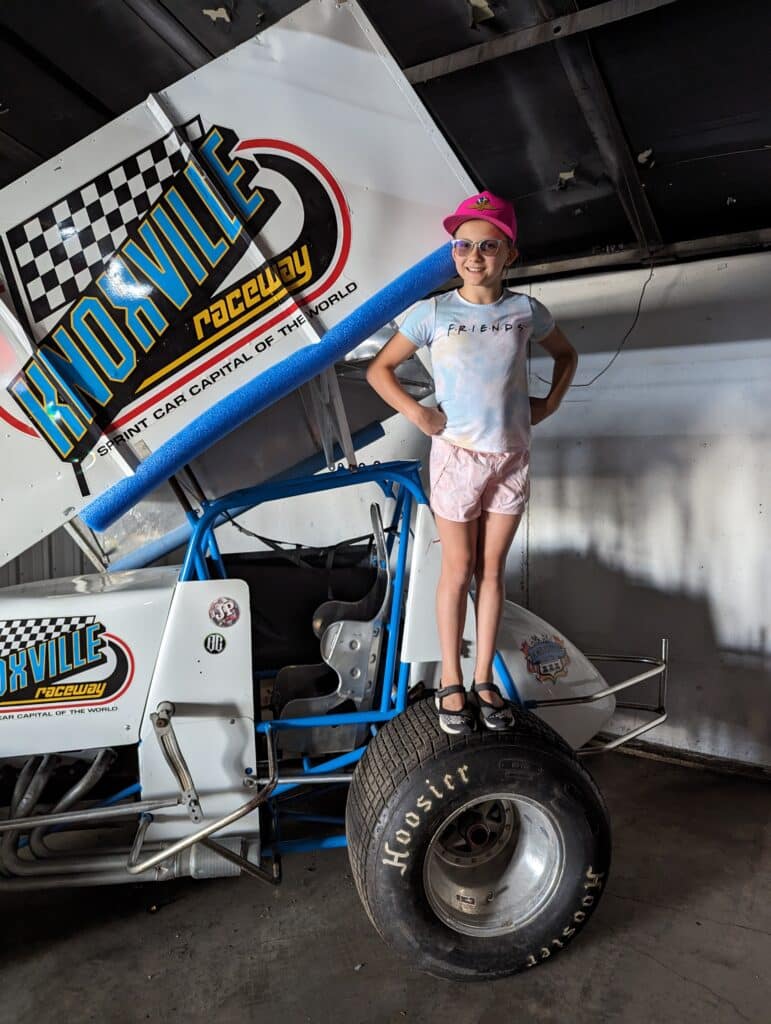 photo of child standing on left rear tire of a sprint car on display at Knoxville Raceway
